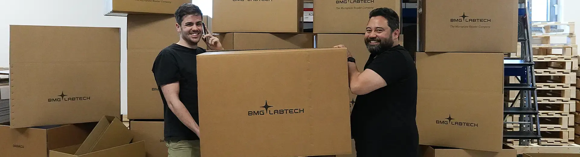 Two warehouse logisticians carrying a cardboard box